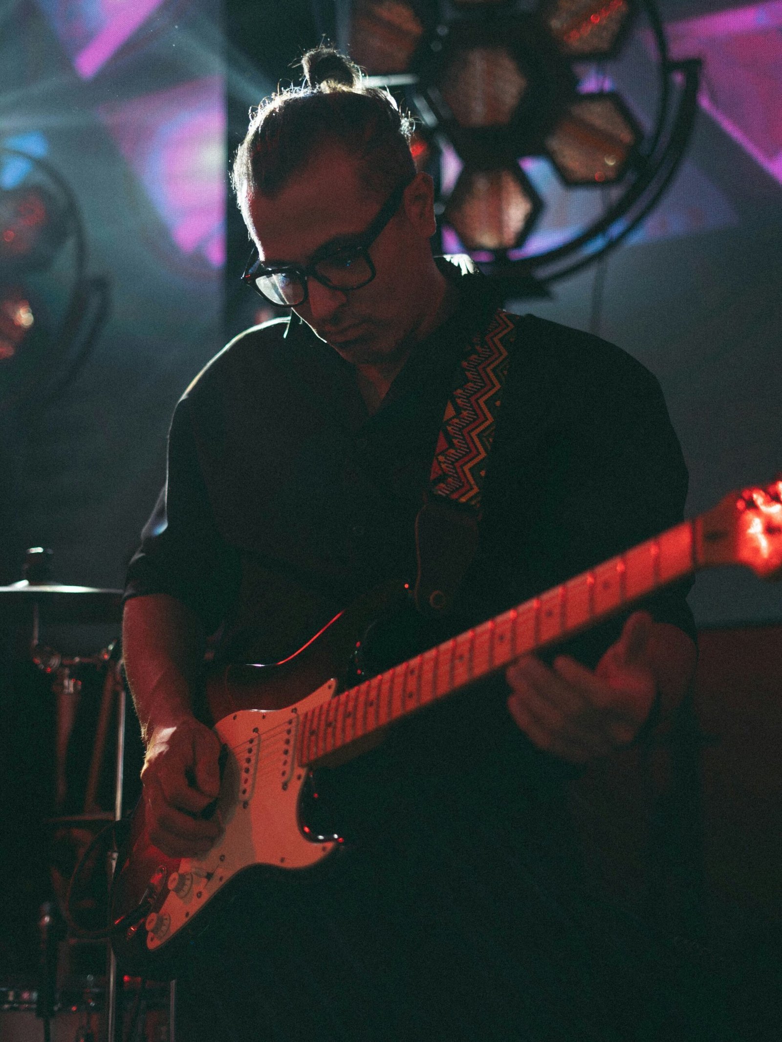 A man playing a guitar in front of a microphone